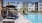 Pool Area with Lounge Chaise Seating, Umbrellas with Palm Trees, and a Clear Pool