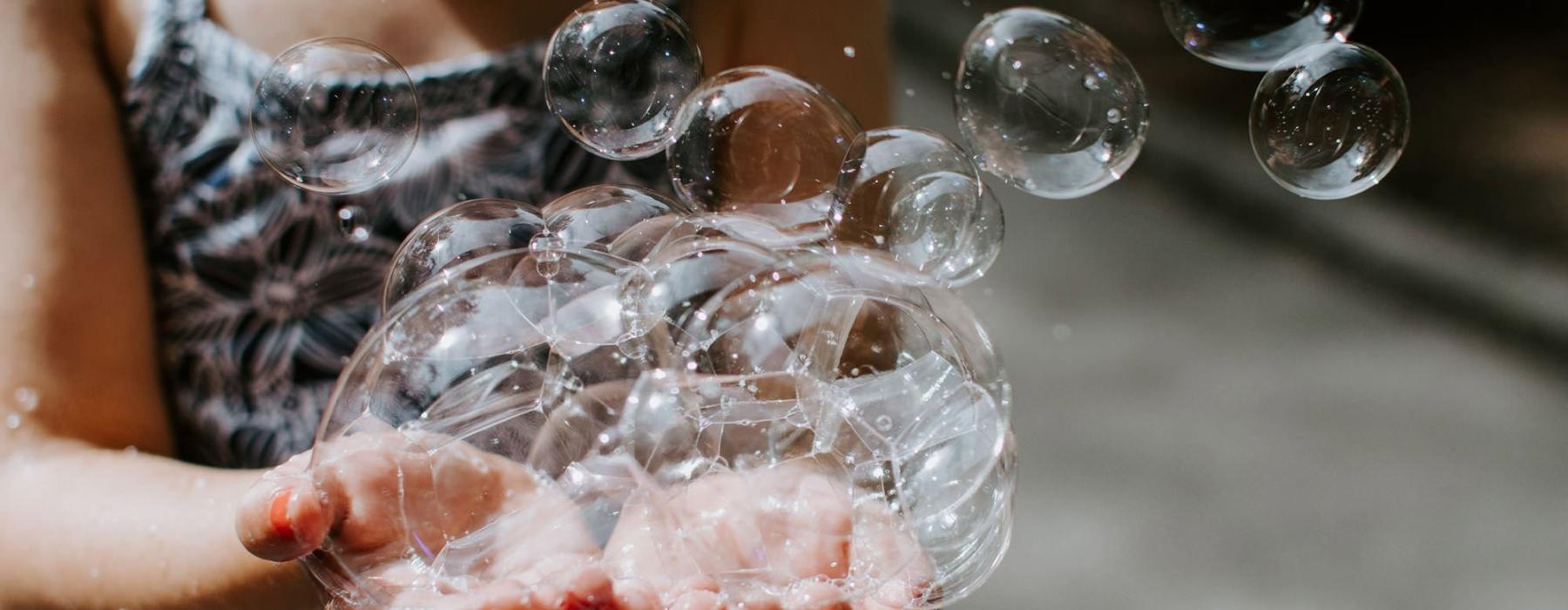 child holding bubbles in her hand as some float away